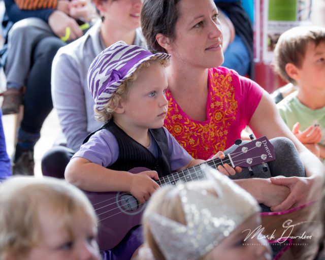 Deep Roots mother and child with ukulele watching puppet show